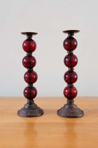 A pair of ruby red candlesticks - four glass bobbins on a metal base